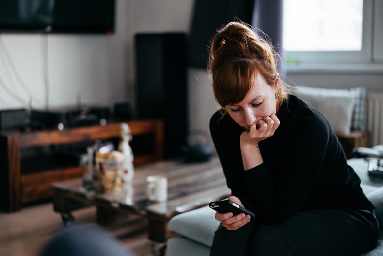A woman sitting down on a couch looking at her phone