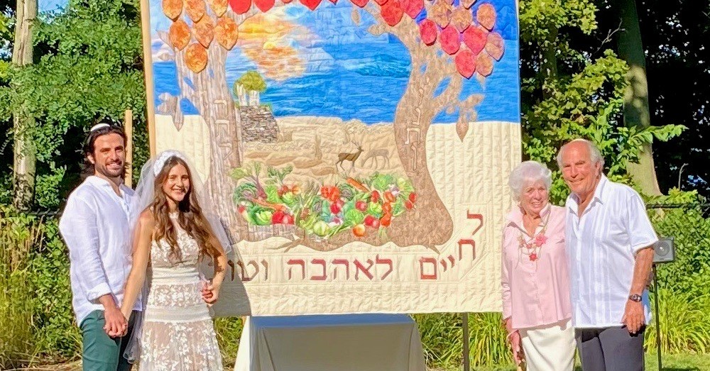 Handmade with love. Erin and Jon Gordon with his grandparents, Abby and Larry Block, beside the chuppah Abby made.