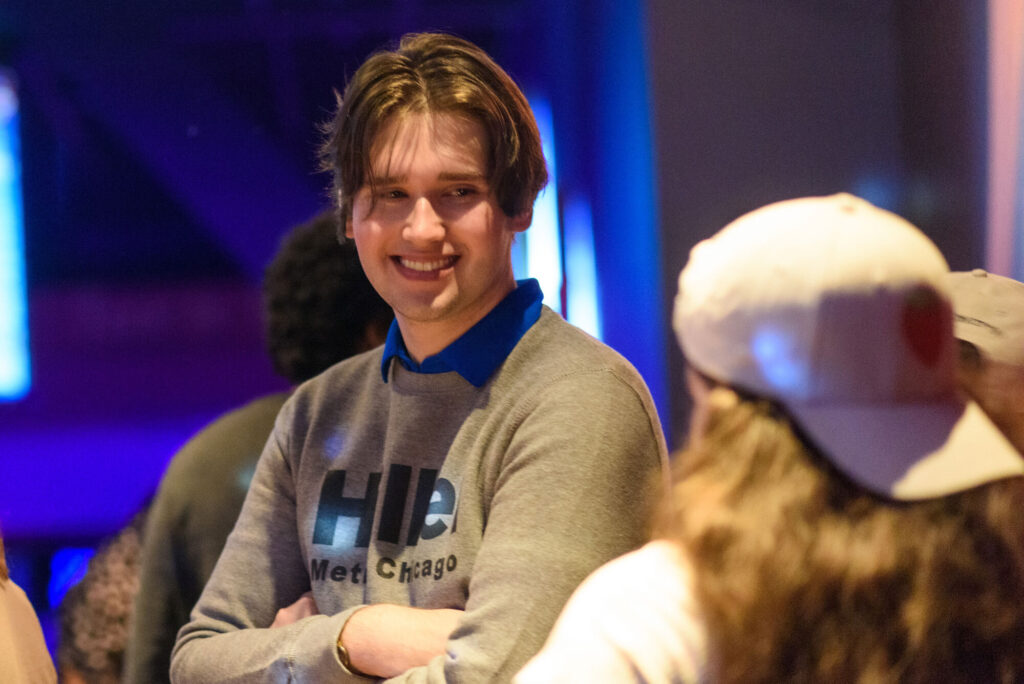 College aged boy smiling with his arms crossed wearing a Hillel Metro Chicago crewneck.