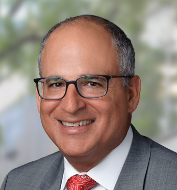 VP of Campus Affairs John Lowenstein head shot smiling wearing glasses a red tie and grey suit.