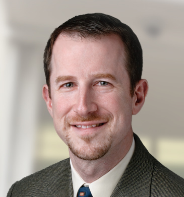 Chief of Staff Jim Rosenberg headshot smiling with brown suit and blue tie.