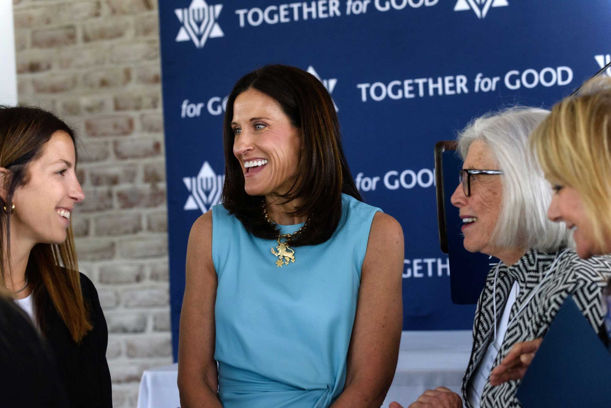 Four women sitting and chatting in front of the JUF logo banner.