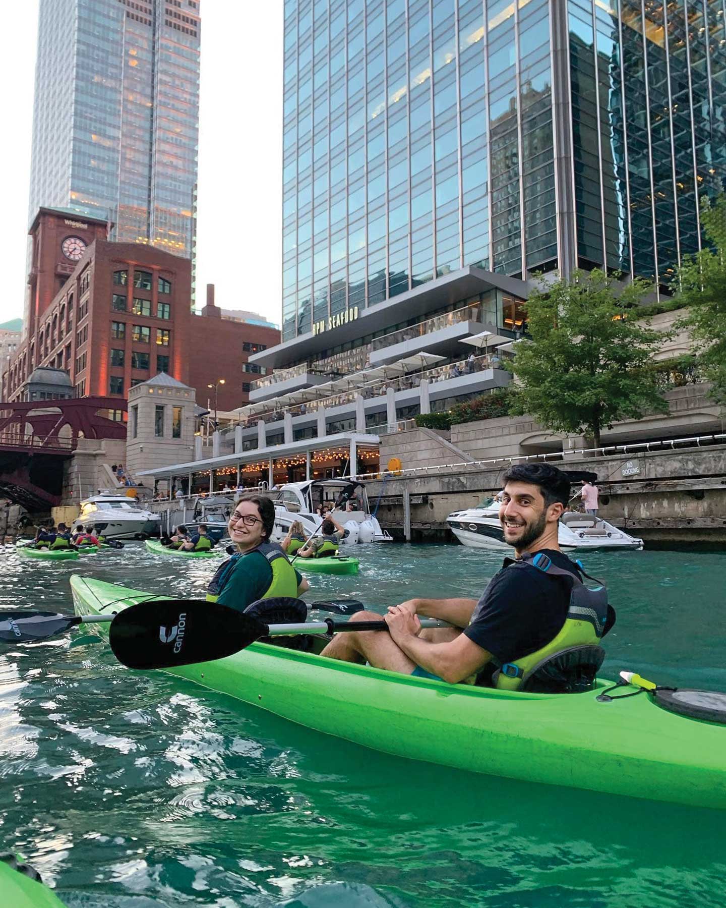 Jewish young adults in bright green kayak's along the Chicago river.