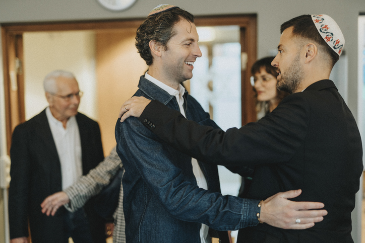 Smiling Jewish men greeting each other during congregation at synagogue