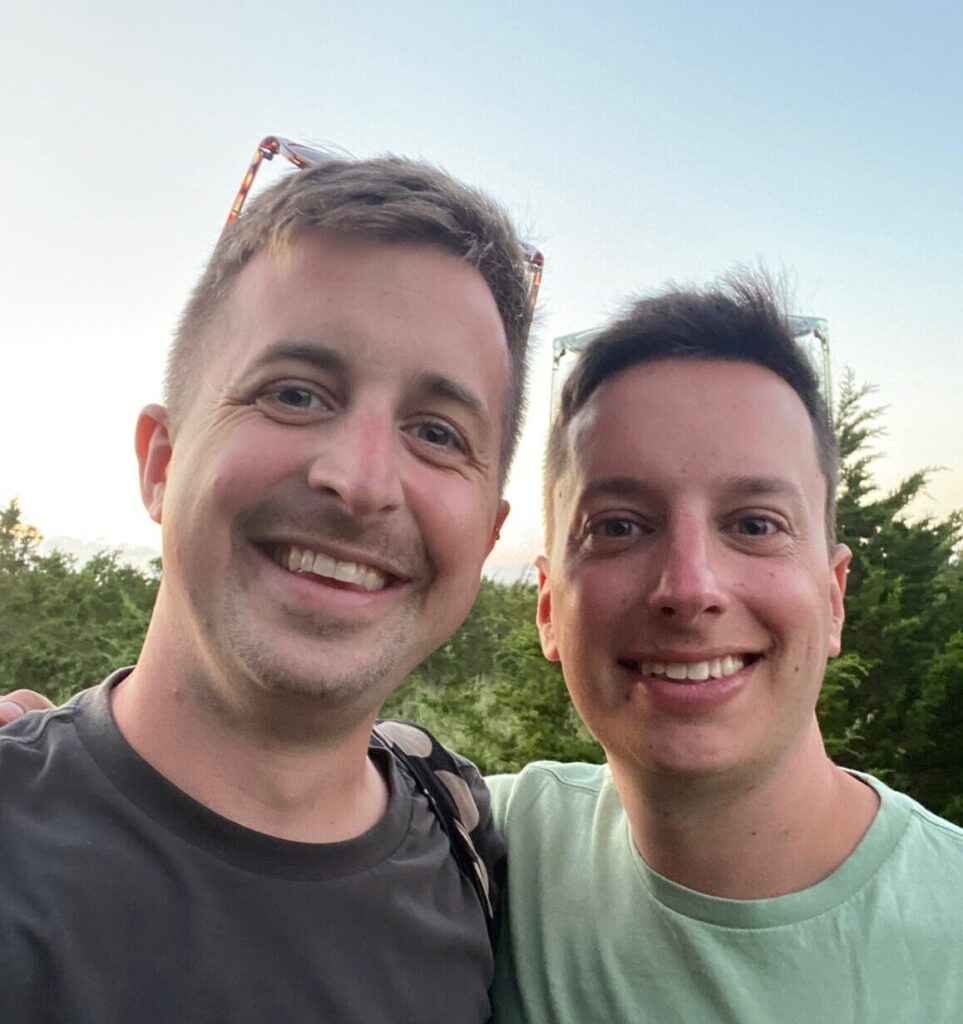 Two men smiling in a selfie as a couple.
