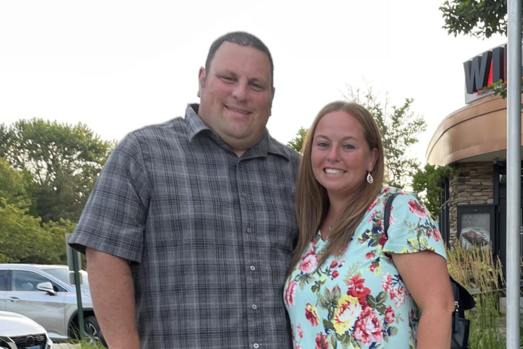 A couple smiling outside a restaurant together.