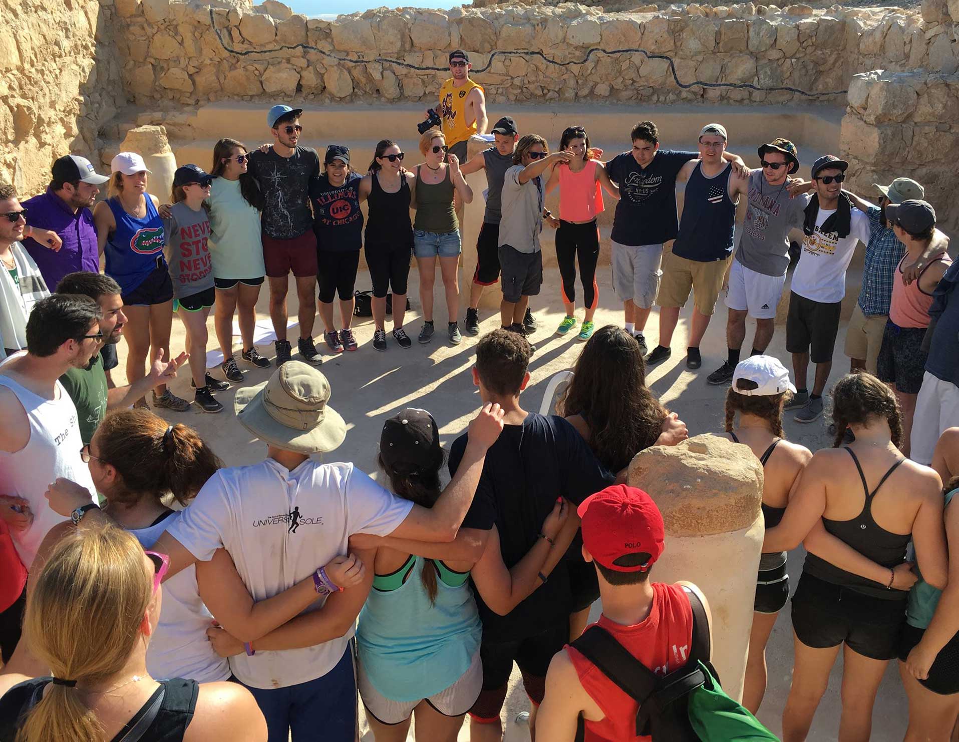 A group of college students standing in a circle with arms around each other smiling in Israel.