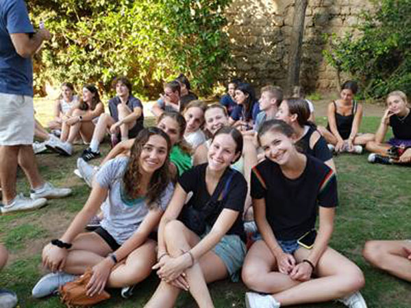 A group of college students sitting on grass smiling during their Onward Israel program.