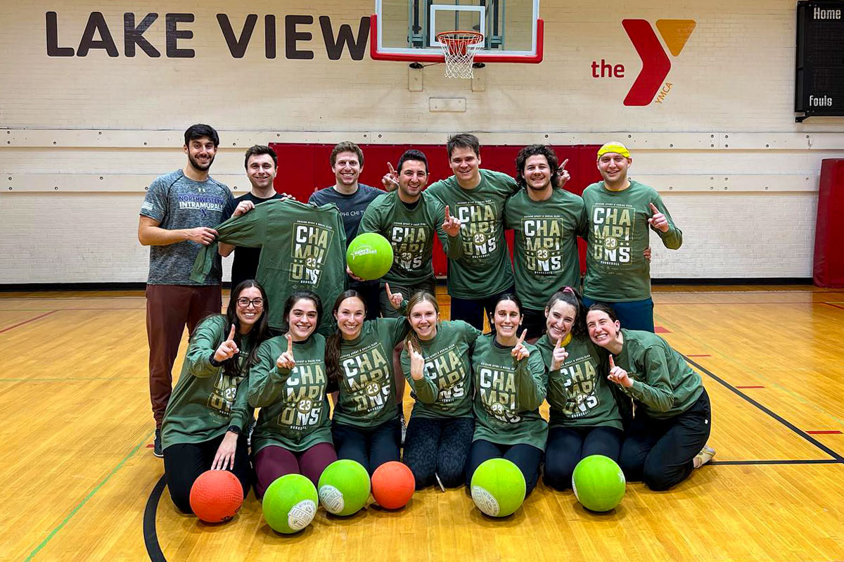 A group of young adults wearing green t shirts posing as a dodgeball team.