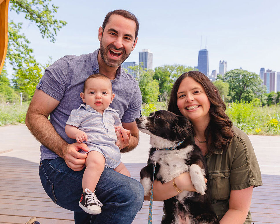 Leah Frydman with her husband, baby and dog in front of the Chicago skyline.