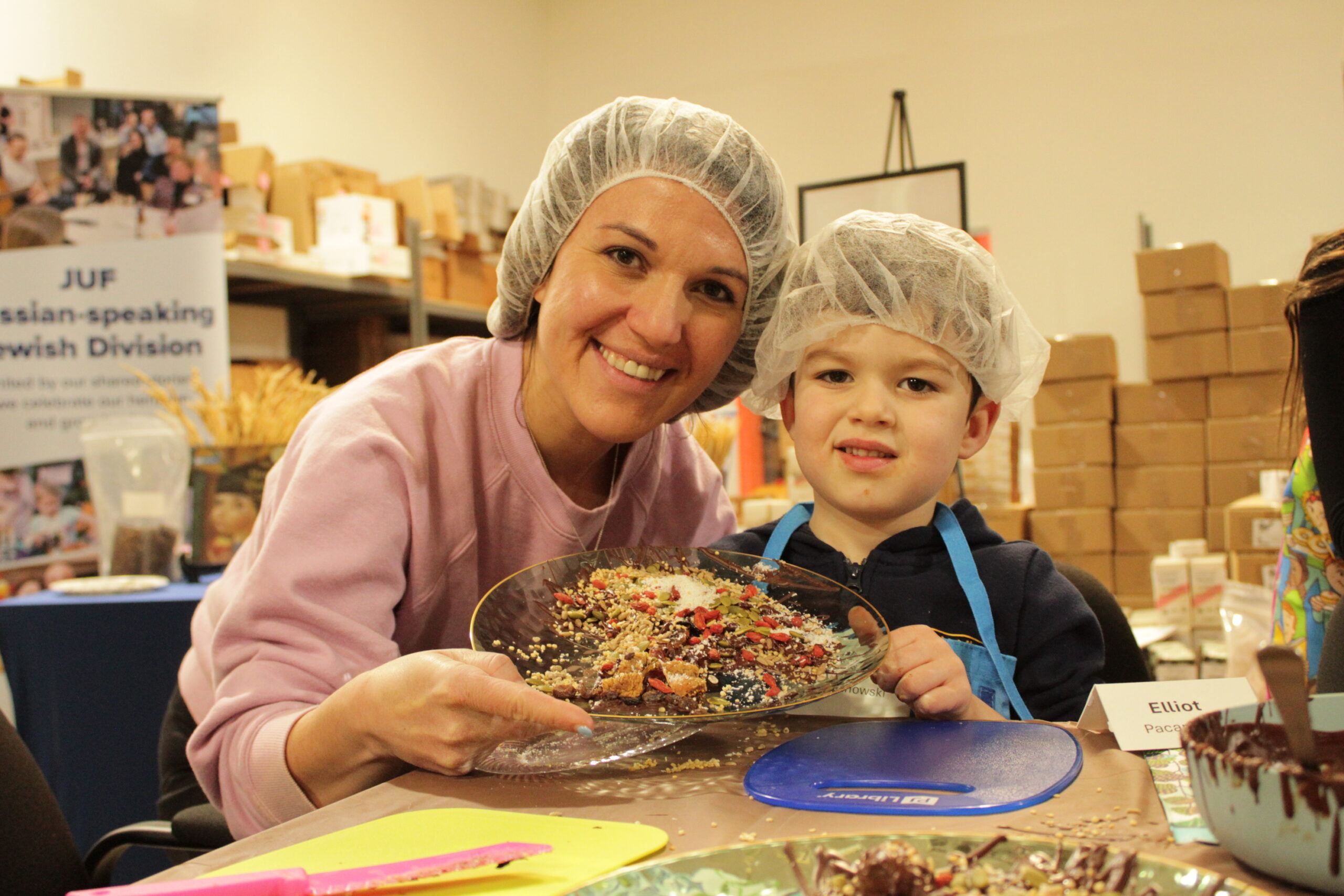 A mother and son wearing plastic hair nets showcasing their chocolate creation.