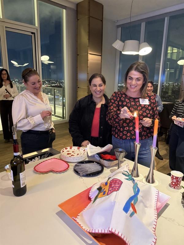 Three women lighting shabbat candles at a galentines event