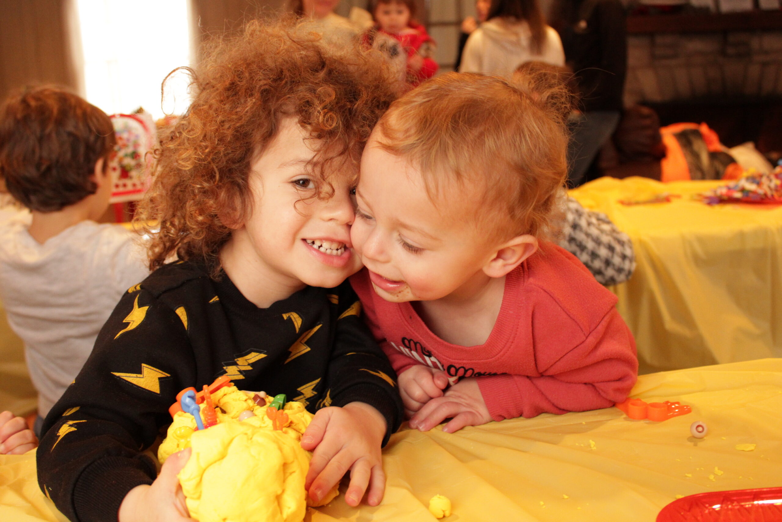 Two small toddlers smiling together with an art project.