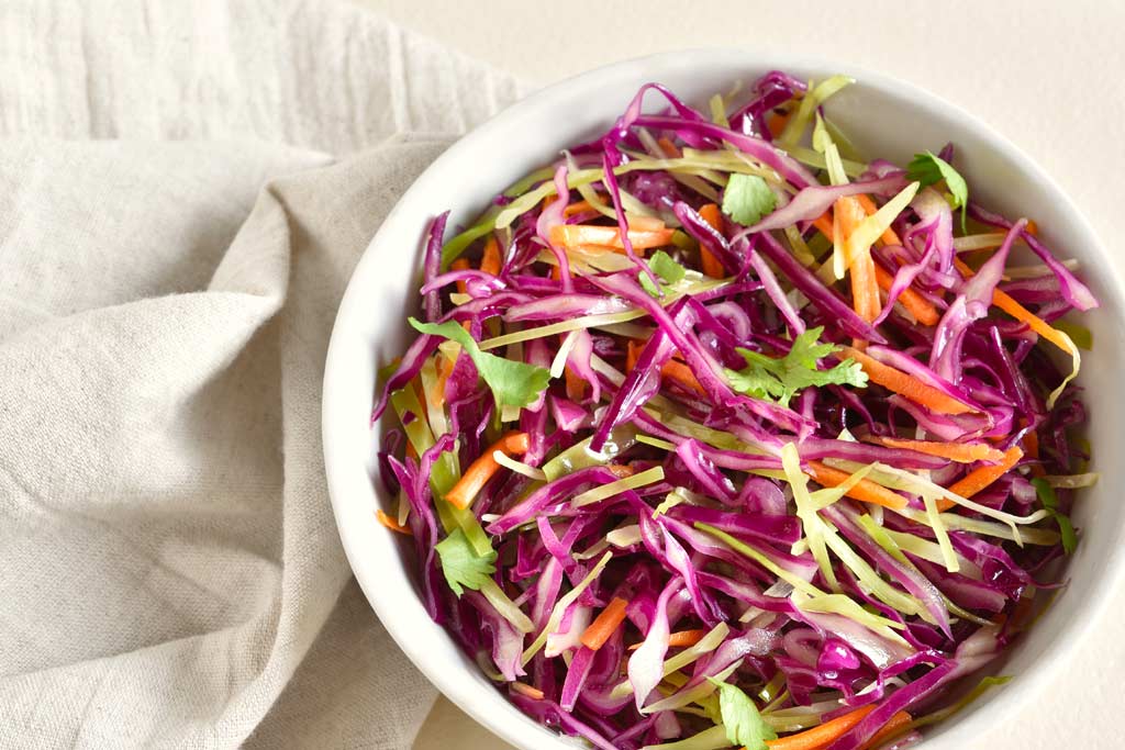 A white bowl of cabbage and carrots slaw.
