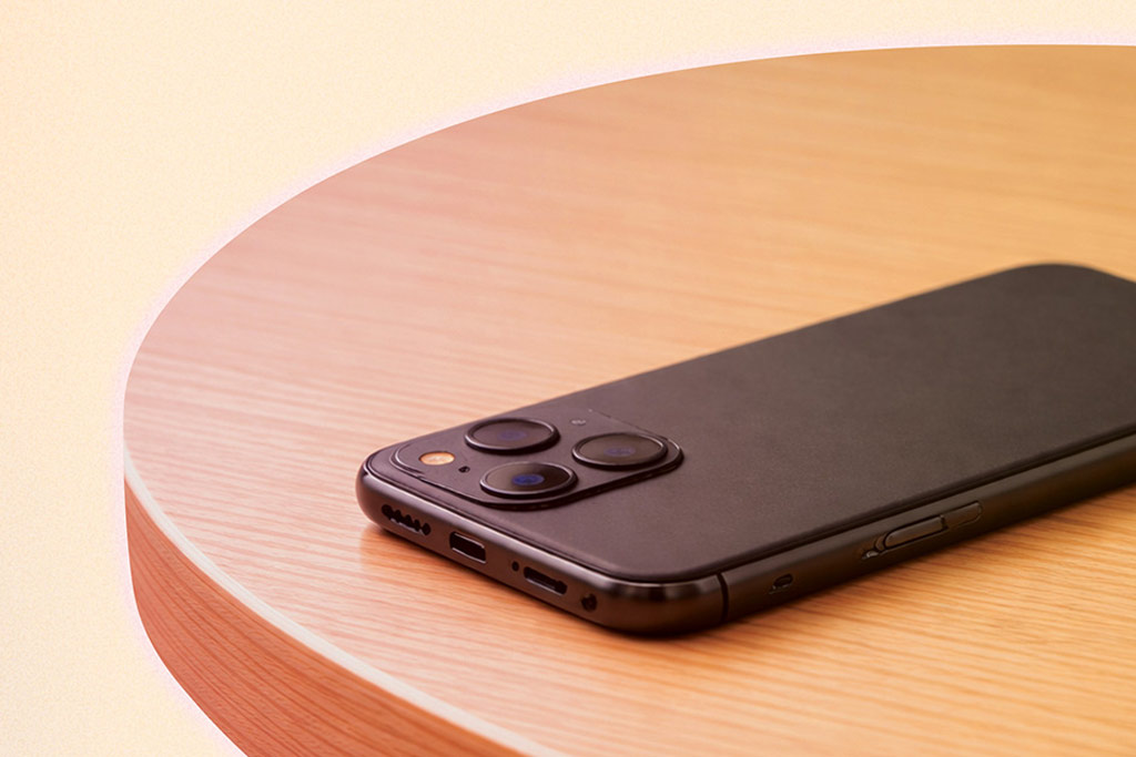 Black iPhone faced down on a circle wooden table.
