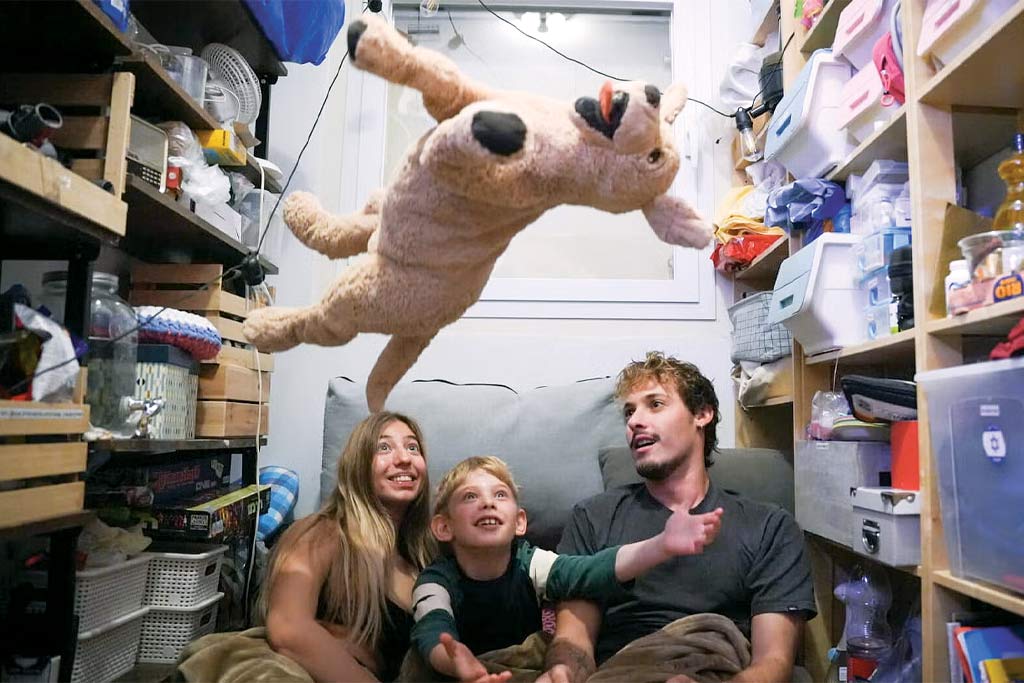 A family with a young kid throwing a stuffed animal in the air as they take cover in a bomb shelter.