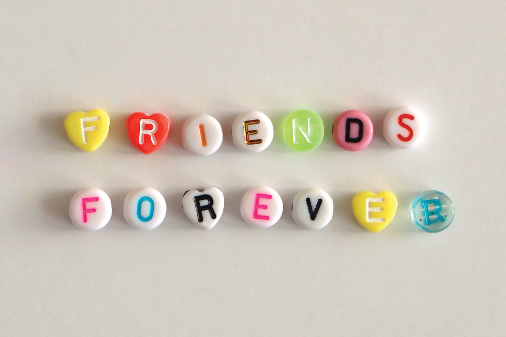 Colorful beads used for bracelet making placed out reading "Friends Forever" one letter on each bead.