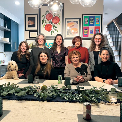 A group of 8 women around a table with a dog.