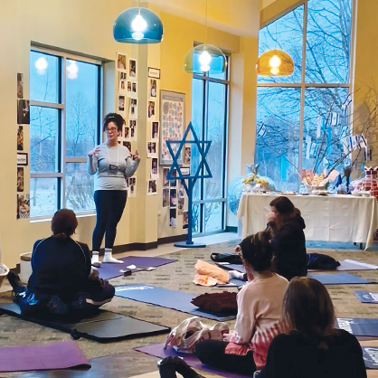 Woman teaching a yoga class with a Jewish star decoration next to her.