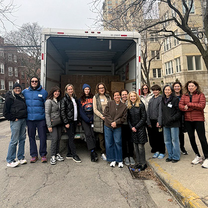 Large group of people standing in front of a delivery truck.