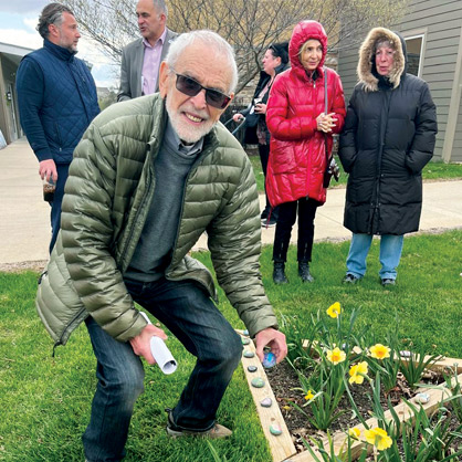 Pictured: Alexander Zupnik, a Holocaust survivor, placing painted rocks at JCC Lake County's Daffodil Memorial Garden.