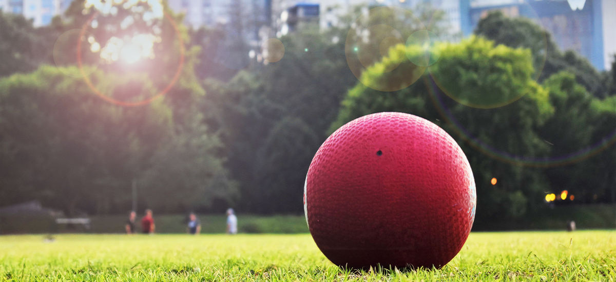 Red kickball on green grass in the sun