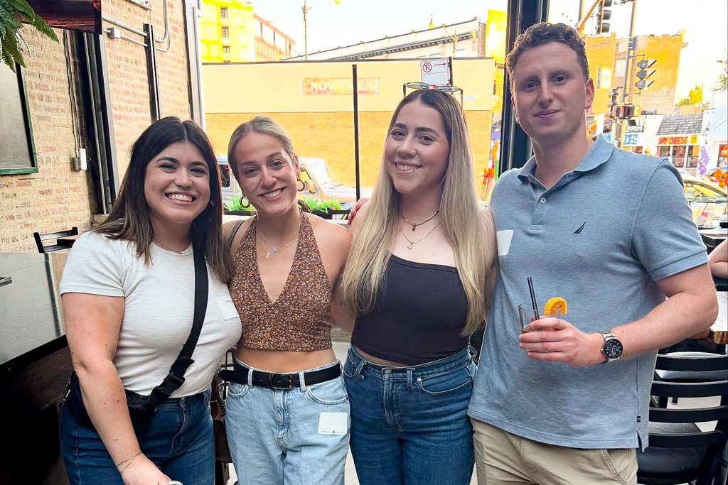 Three young women and one young man enjoying drinks at a happy hour