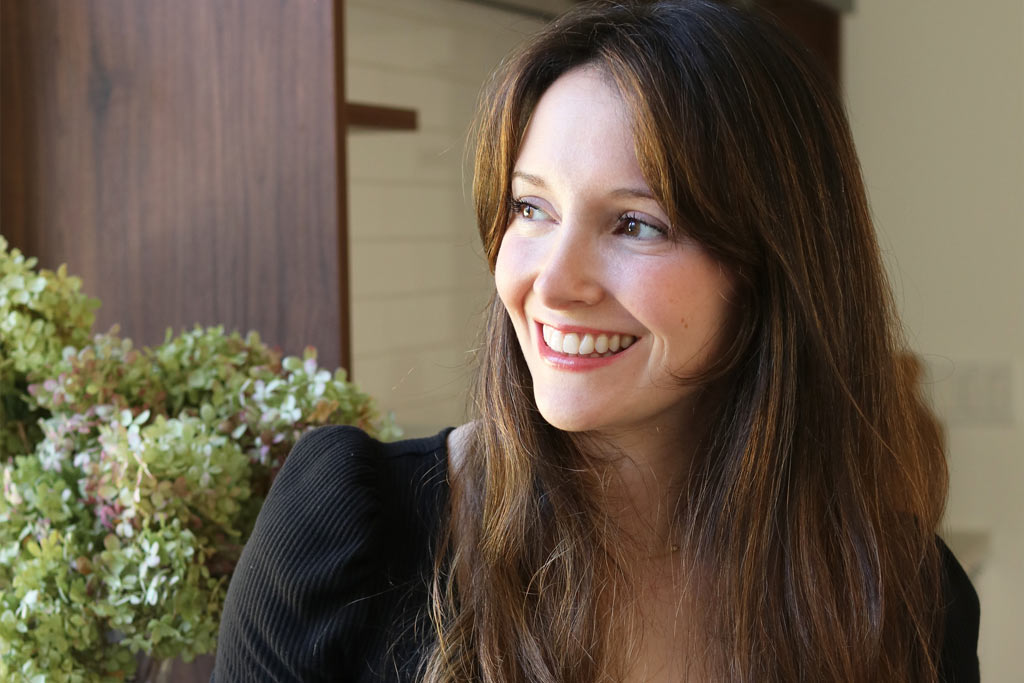 a photo of a women smiling, looking off to the side.